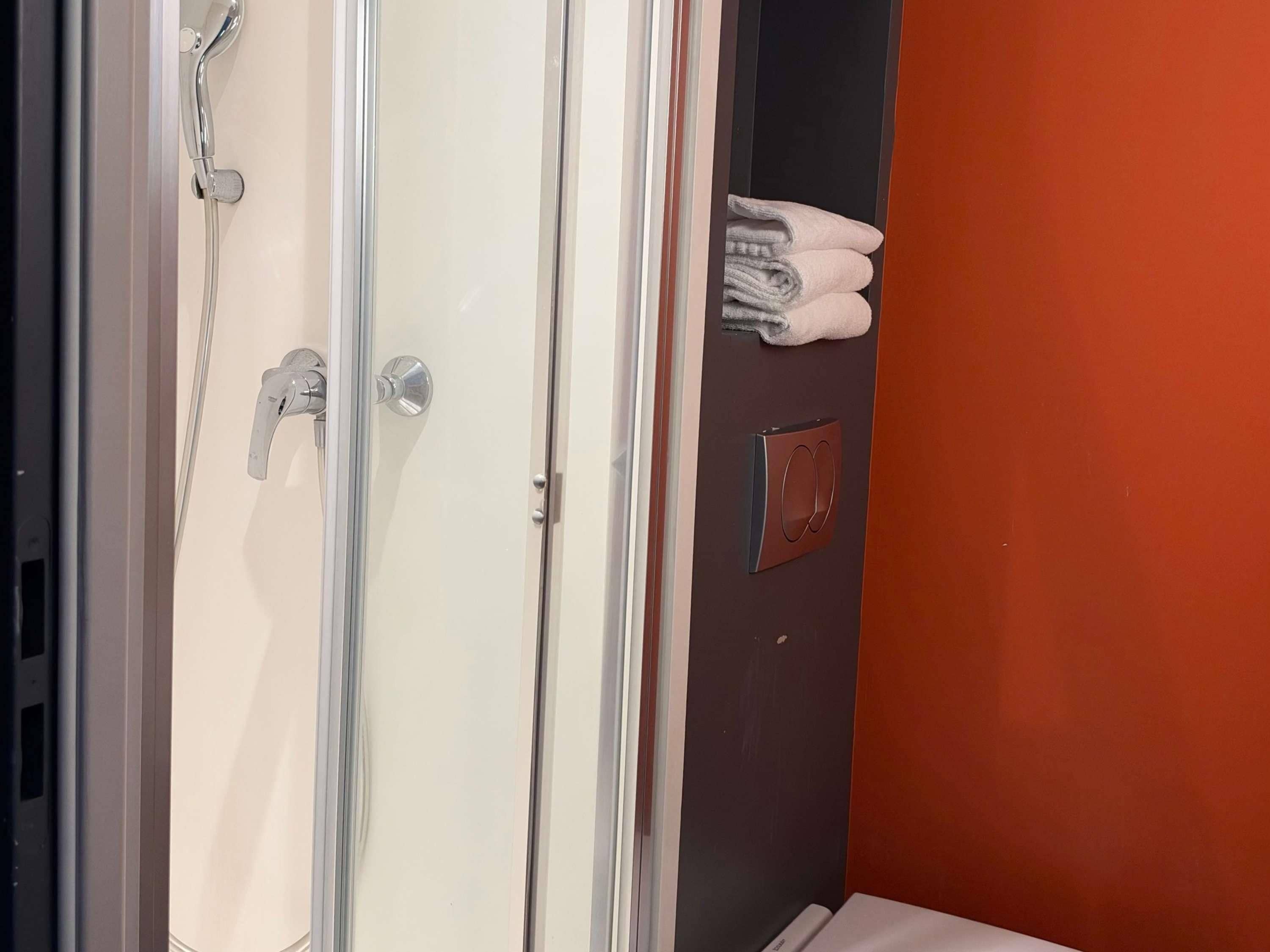Une salle de bain avec une douche, un porte-serviettes et une porte dotée d’une poignée.