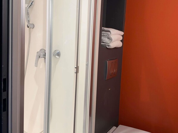 A bathroom with a shower, a towel rack, and a door with a handle.