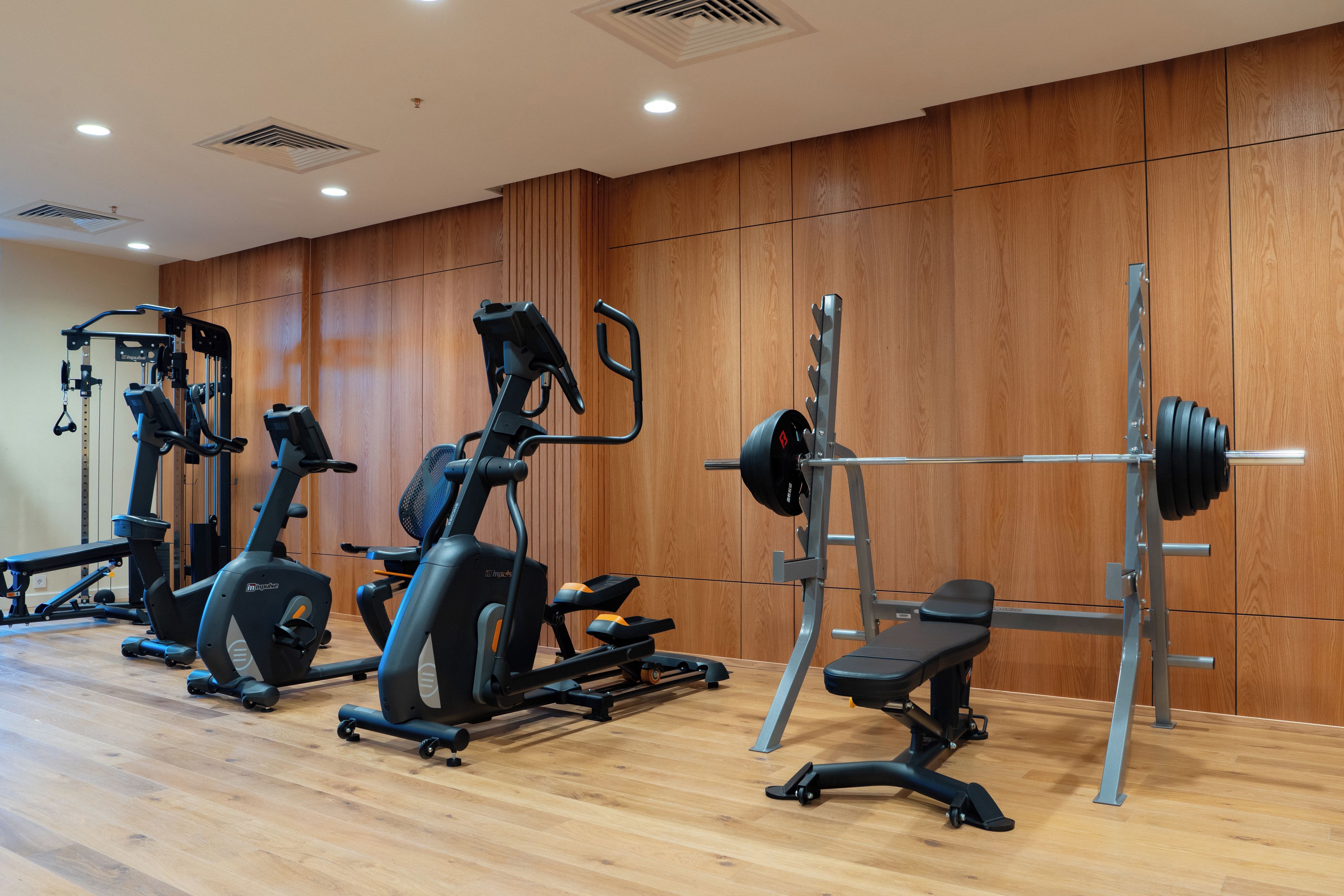 Une salle de sport équipée de divers appareils, notamment des tapis de course, un banc de développé couché et un support à squats.