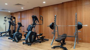 Une salle de sport équipée de divers appareils, notamment des tapis de course, un banc de développé couché et un support à squats.