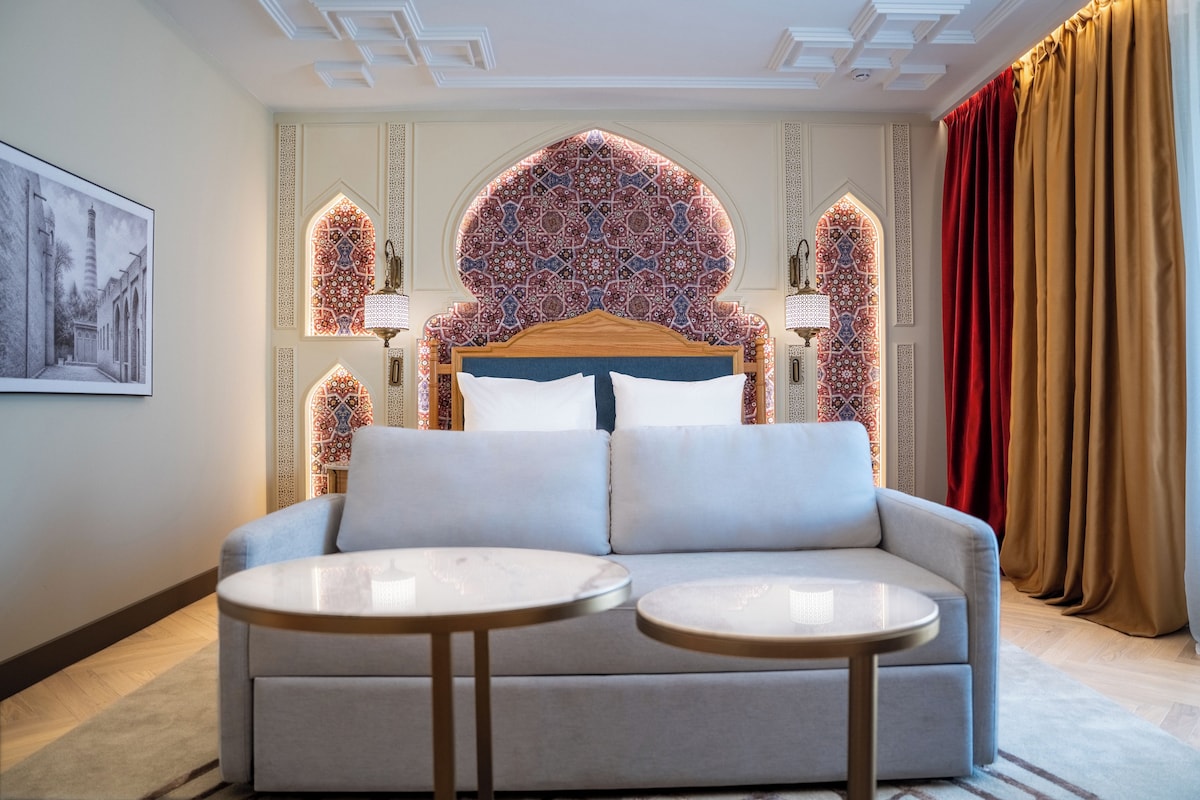 Una habitación de hotel con una cama grande, dos mesitas de noche y vista a una pared con diseño.