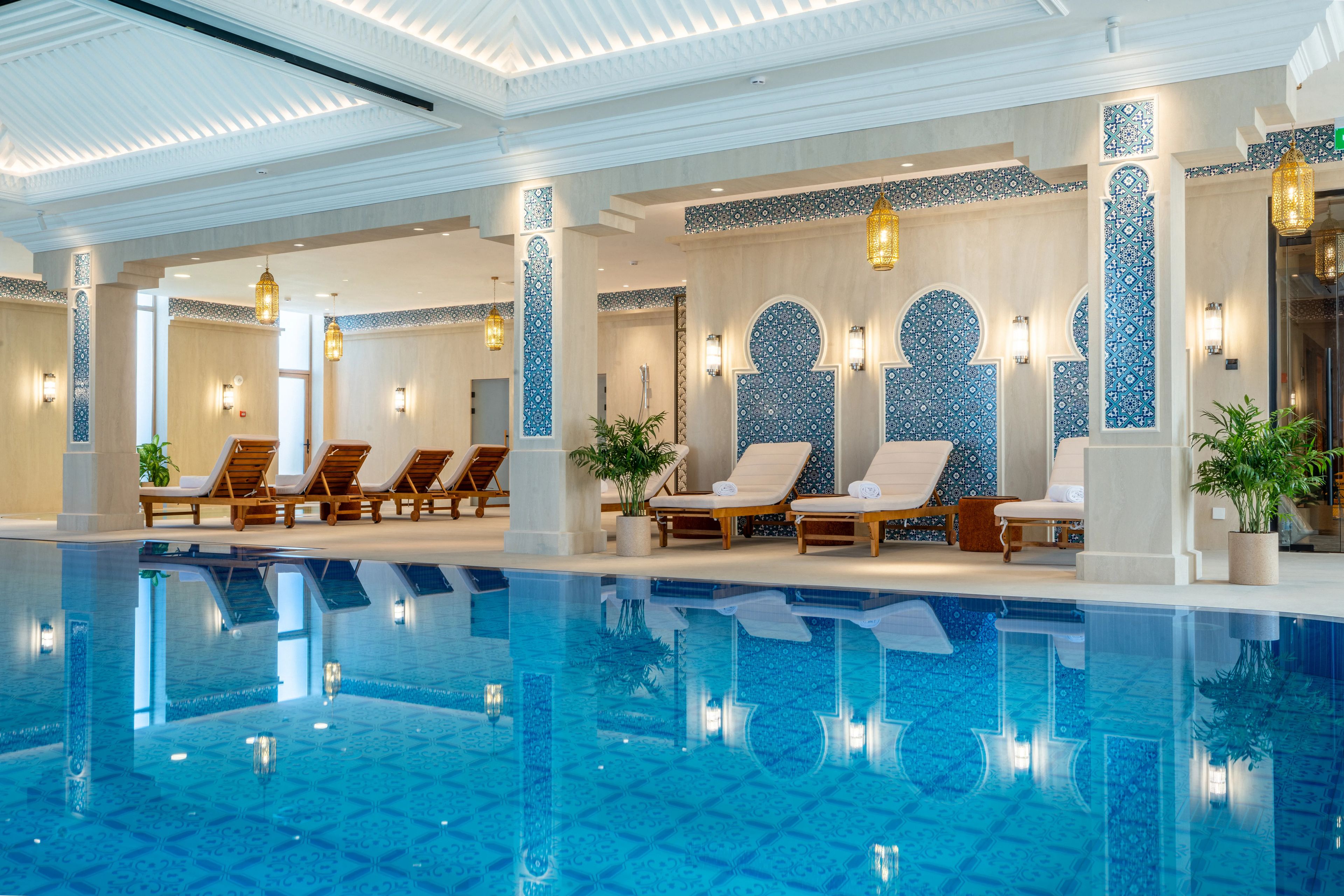 Zona junto a la piscina con sillones de descanso y una gran piscina interior.