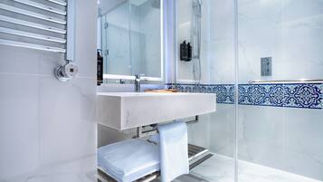 Casa de banho moderna com cabine de duche em vidro, lavatório branco e painel de azulejos azul e branco.