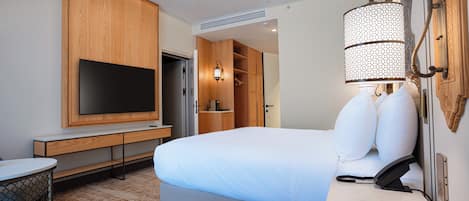 Una habitación de hotel con cama, televisión, escritorio y silla.