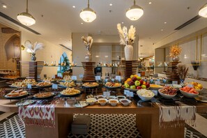 A buffet with various food items and a decorative centerpiece. - Mercure Khiva (Khiva)