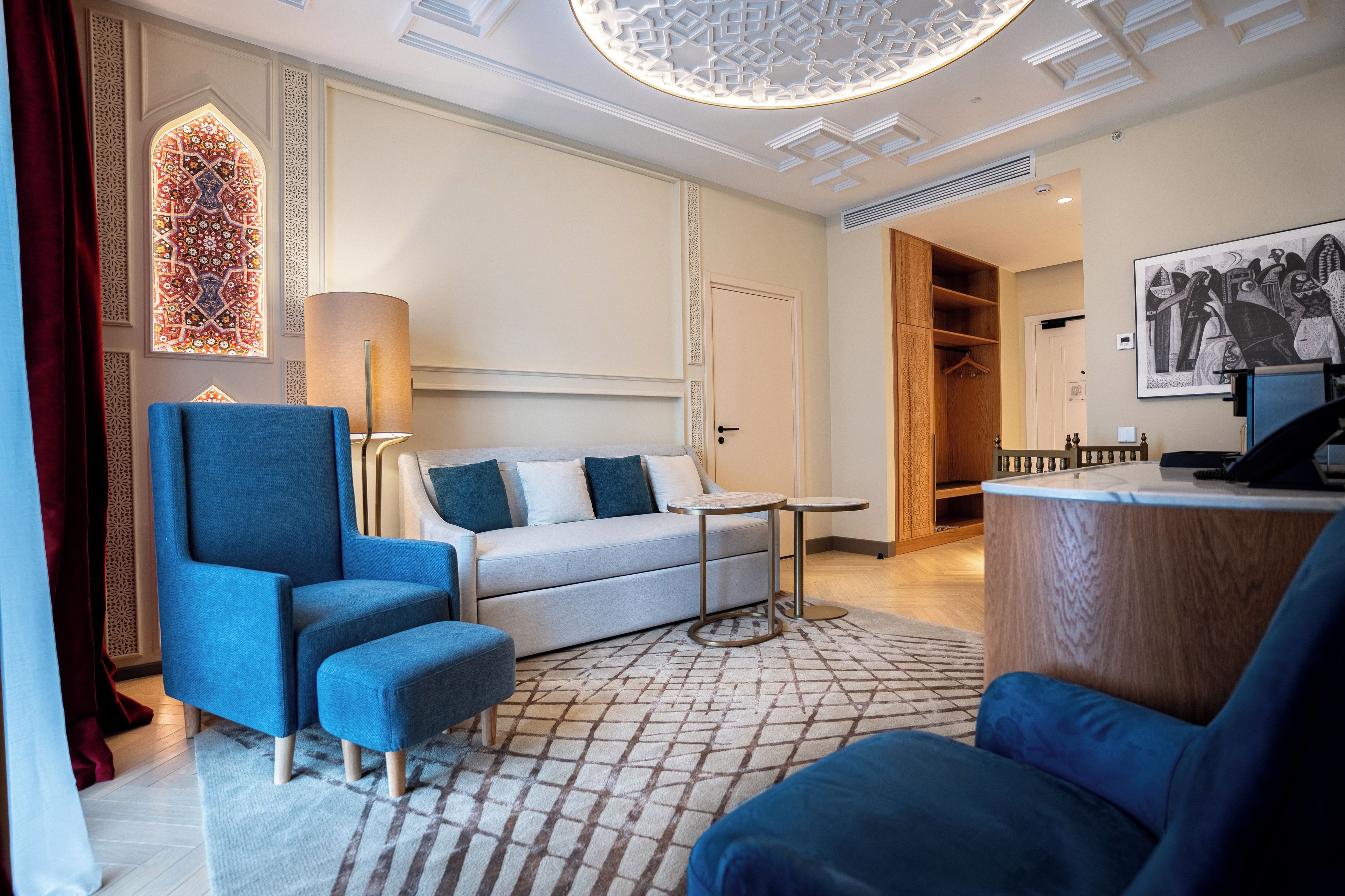 A modern hotel room with a sofa, armchair, and a small table.