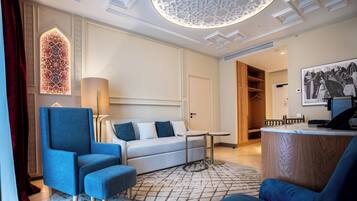 A modern hotel room with a sofa, armchair, and a small table.