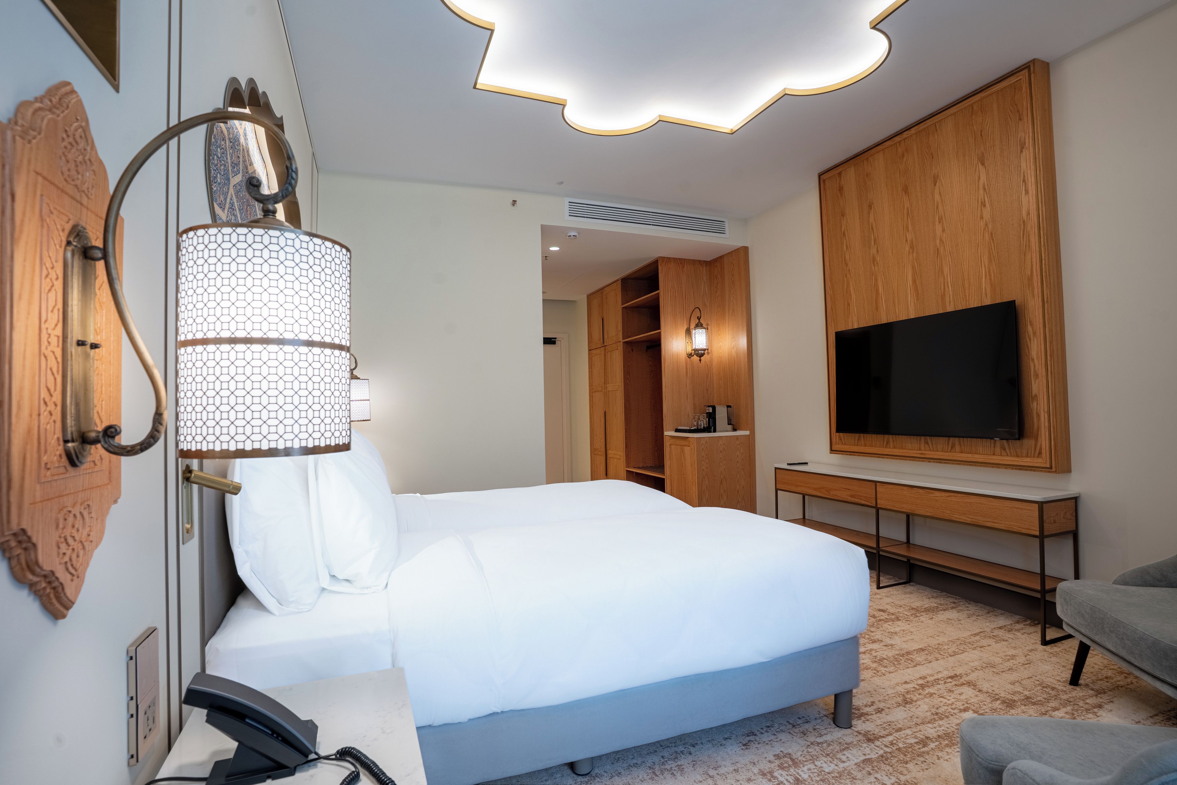 Quarto de hotel com cama, televisão, escrivaninha e guarda-roupa.