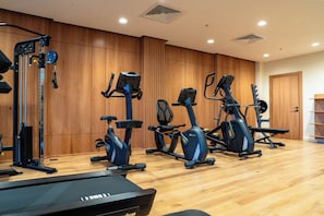 Un gimnasio con varias máquinas de ejercicio, una cinta de correr y paneles de madera.