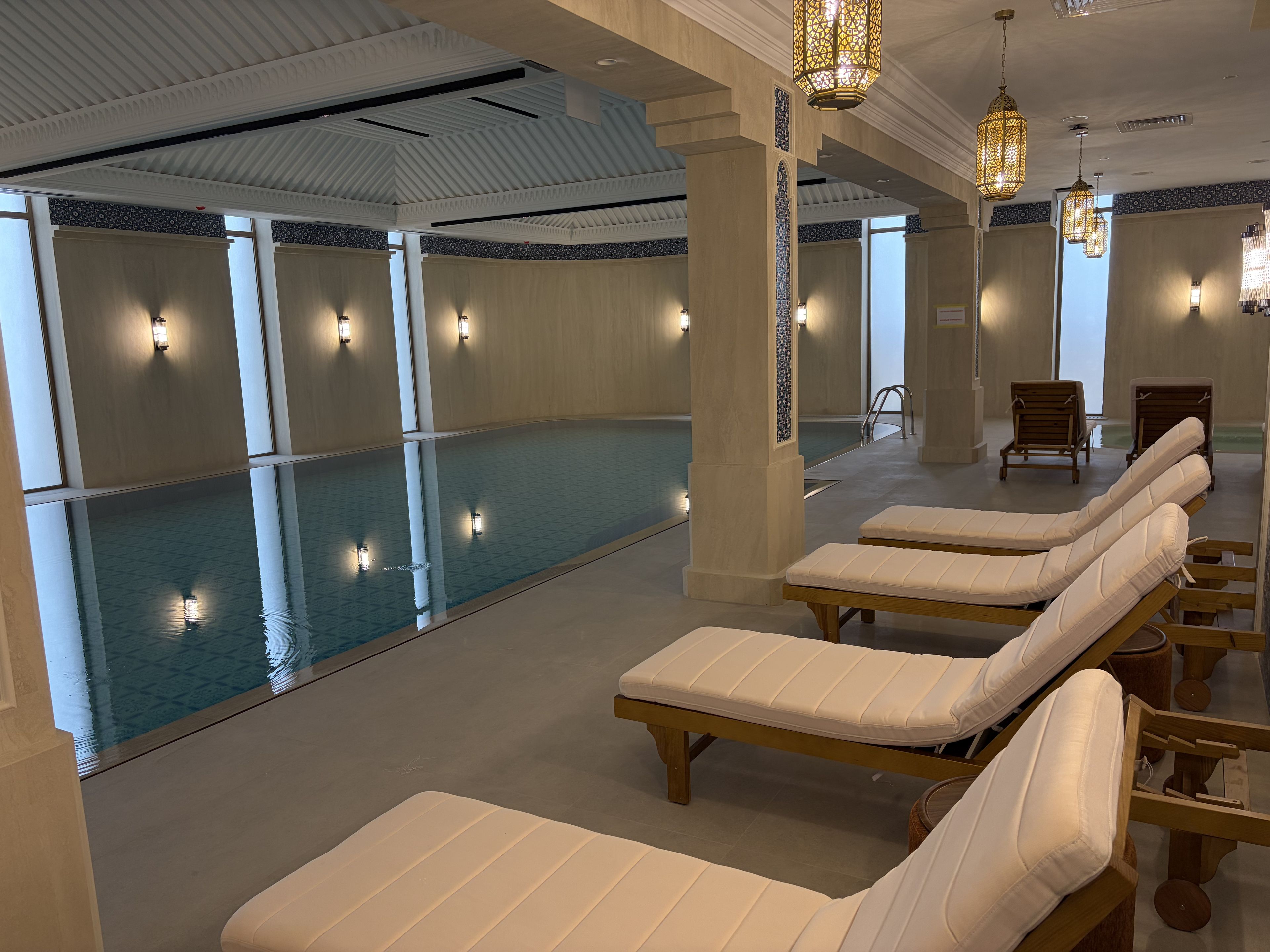 Ein Wellnessbereich mit Pool, Liegestühlen und dekorativer Beleuchtung.