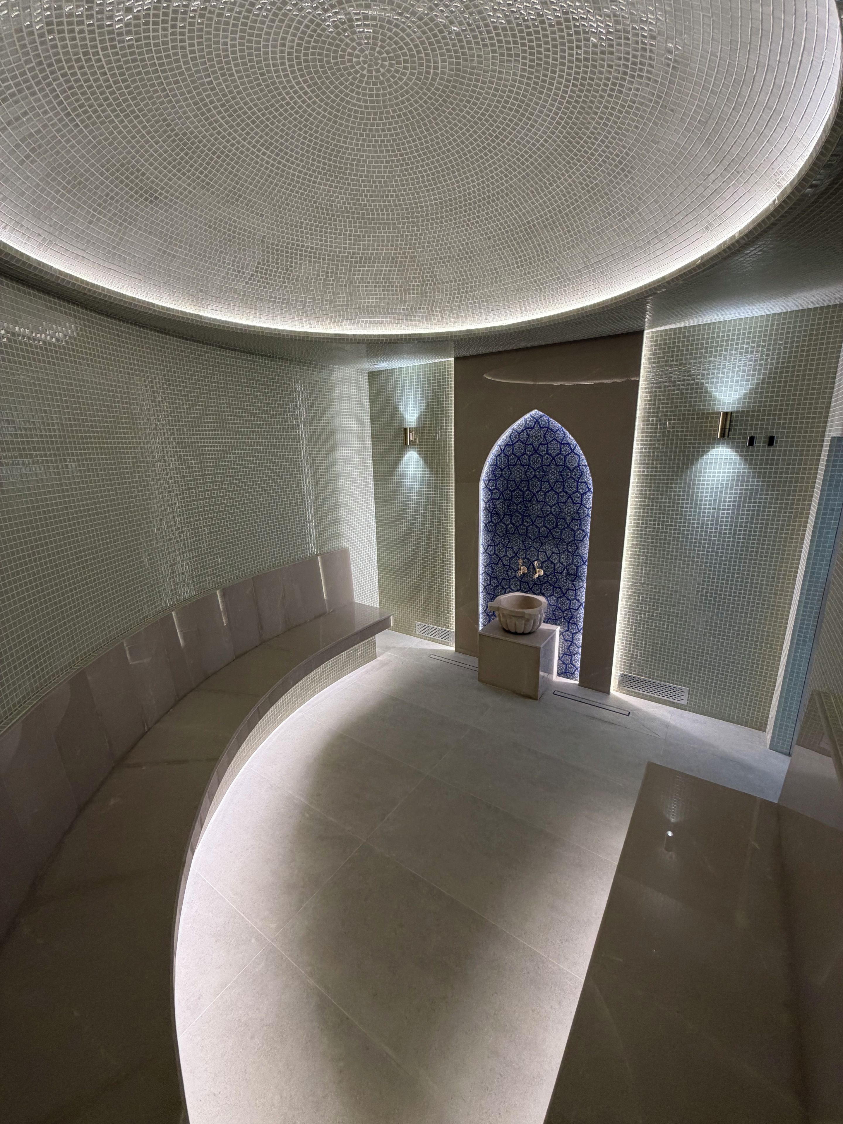 A modern interior with a curved seating area, a patterned wall, and a decorative blue archway.