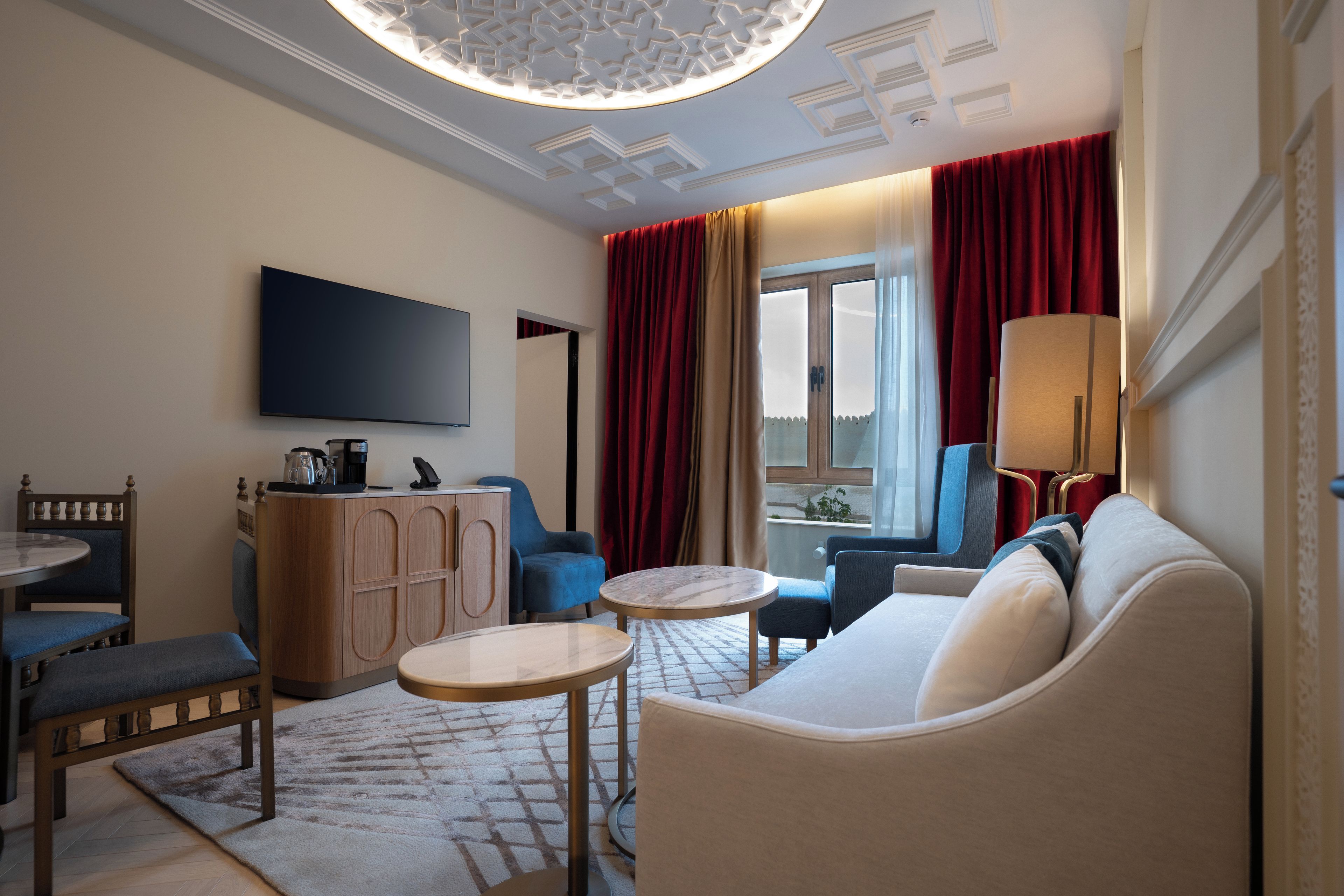 Una sala de estar moderna con un televisor de pantalla plana, un sofá, una mesa de centro y un comedor con una silla y una mesa.