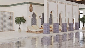 Ein Wellnessbereich mit Pool, Liegestühlen und dekorativen Säulen.