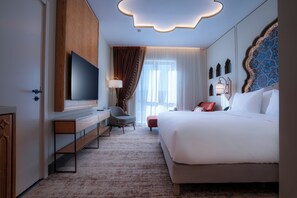 A hotel room with a large bed, a TV, a desk, and a chair. - Mercure Khiva (Khiva)