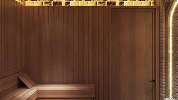 Una habitación de madera con un banco, una puerta y una pared de ladrillo con una tira de luz.