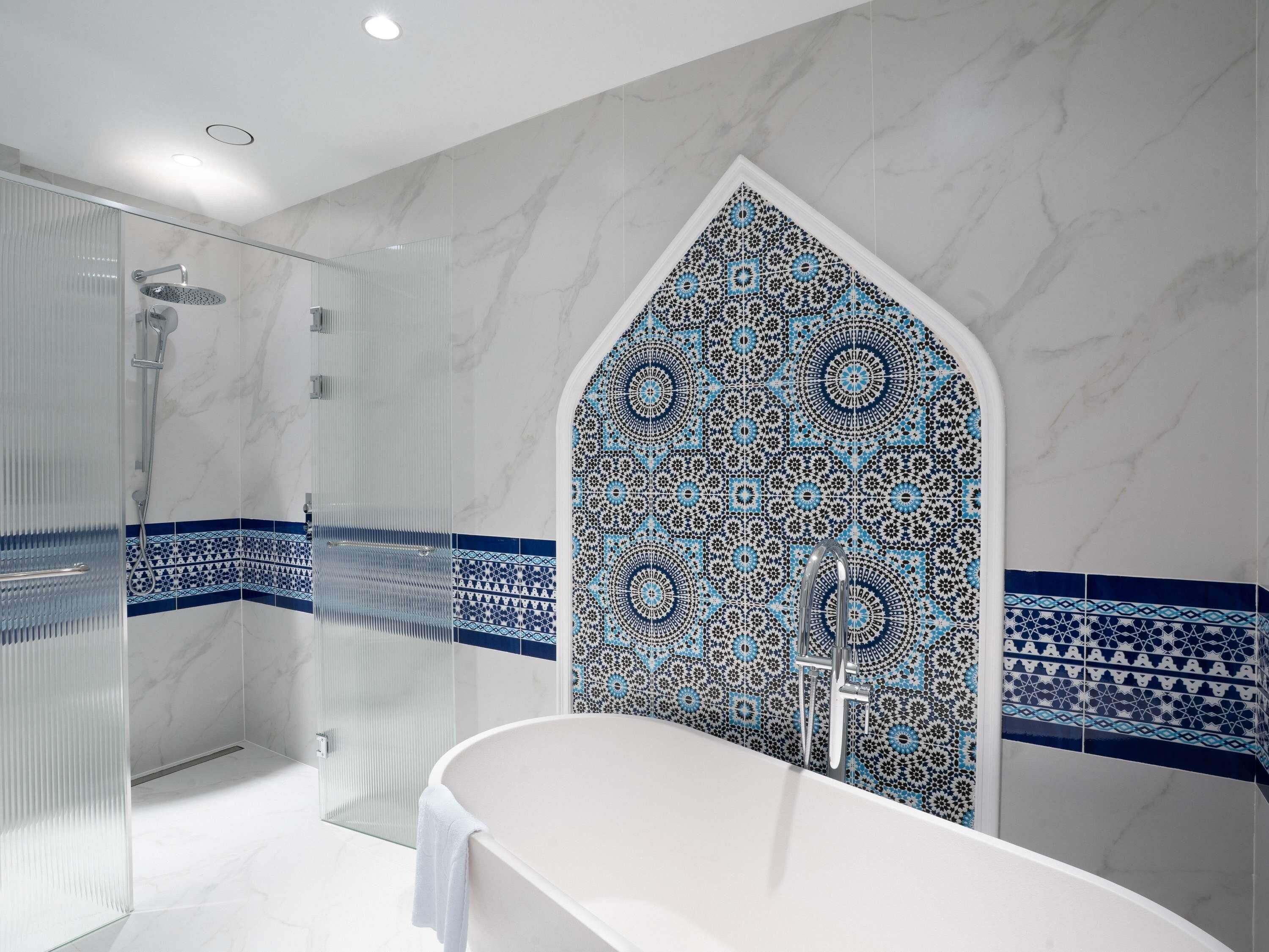 A modern bathroom with a glass shower enclosure, a freestanding bathtub, and decorative tile patterns.