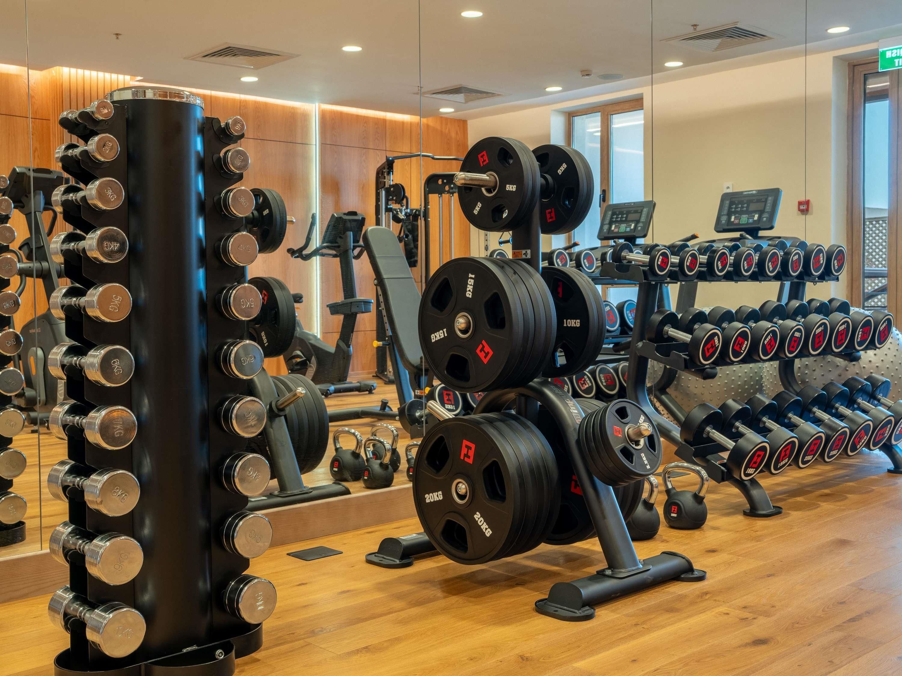 Ein Fitnessstudio mit Krafttrainingsgeräten, Trainingsmaschinen und einem digitalen Bildschirm.
