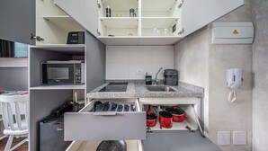 Cocina compacta con microondas, cafetera y pileta.