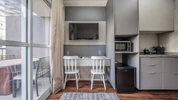 Une cuisine compacte équipée d’un four à micro-ondes, d’un petit réfrigérateur et d’une fenêtre donnant sur un balcon.