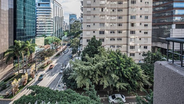 Un paisaje urbano con edificios modernos, cielo despejado y una calle con coches y árboles.