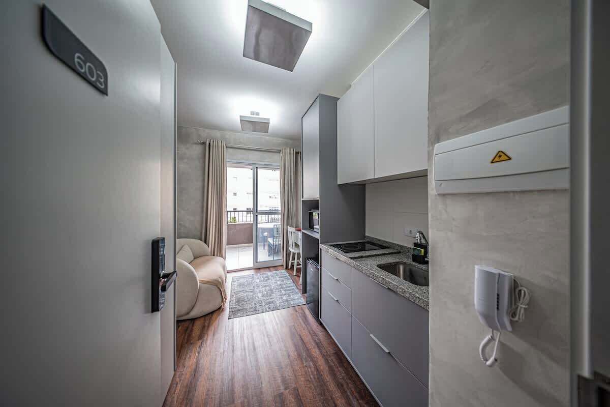 Une cuisine moderne équipée d’une cuisinière intégrée, d’un four à micro-ondes et d’un évier. Une porte coulissante donne accès à un balcon offrant une vue sur la ville.