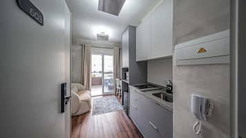Une cuisine moderne équipée d’une cuisinière intégrée, d’un four à micro-ondes et d’un évier. Une porte coulissante donne accès à un balcon offrant une vue sur la ville.