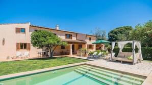 A pool area with a clear blue pool, lounge chairs, and a pergola with a canopy. - Private Pool Villa in Pollensa (Pollença)