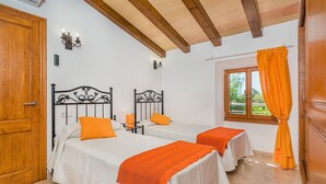 A room with two beds, a window with curtains, and a wooden door. - Private Pool Villa in Pollensa (Pollença)