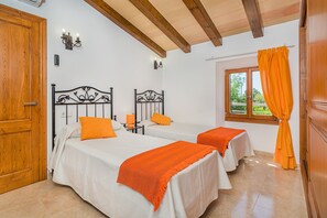 A room with two beds, a window with curtains, and a wooden door. - Private Pool Villa in Pollensa (Pollença)