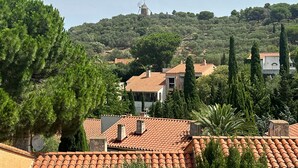 Et villaområde på en skråning med terracotta-tag, en vindmølle og frodig vegetation.