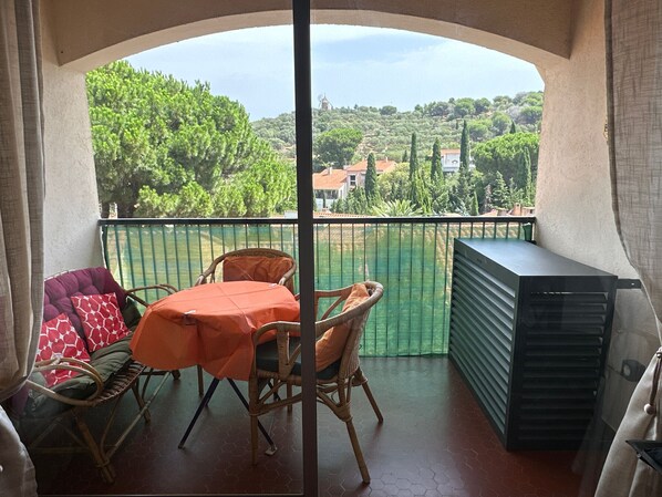 A balcony with a table and chairs, a view of a village, and a green fence. - T2 Apartment with AC - 4 guests in Collioure (Collioure)