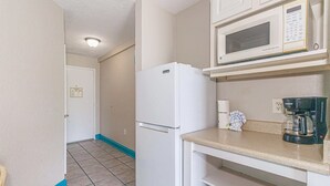 A compact kitchenette with a white refrigerator, a microwave, and a coffee maker on the countertop. - Sea Mist 51202 Cozy Ocean View Studio (Myrtle Beach)