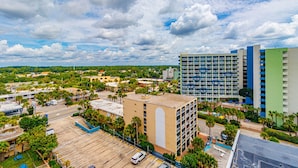 A multi-story hotel with balconies, a parking lot, and a view of the surrounding urban area. - Sea Mist 51202 Cozy Ocean View Studio (Myrtle Beach)