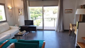 En moderne stue med en sofa, et fjernsyn og et spiseområde med stole.