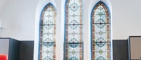 A room with three tall, narrow windows featuring intricate stained glass designs.