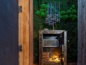 An open wooden door revealing a fireplace with books and a metal structure above it.