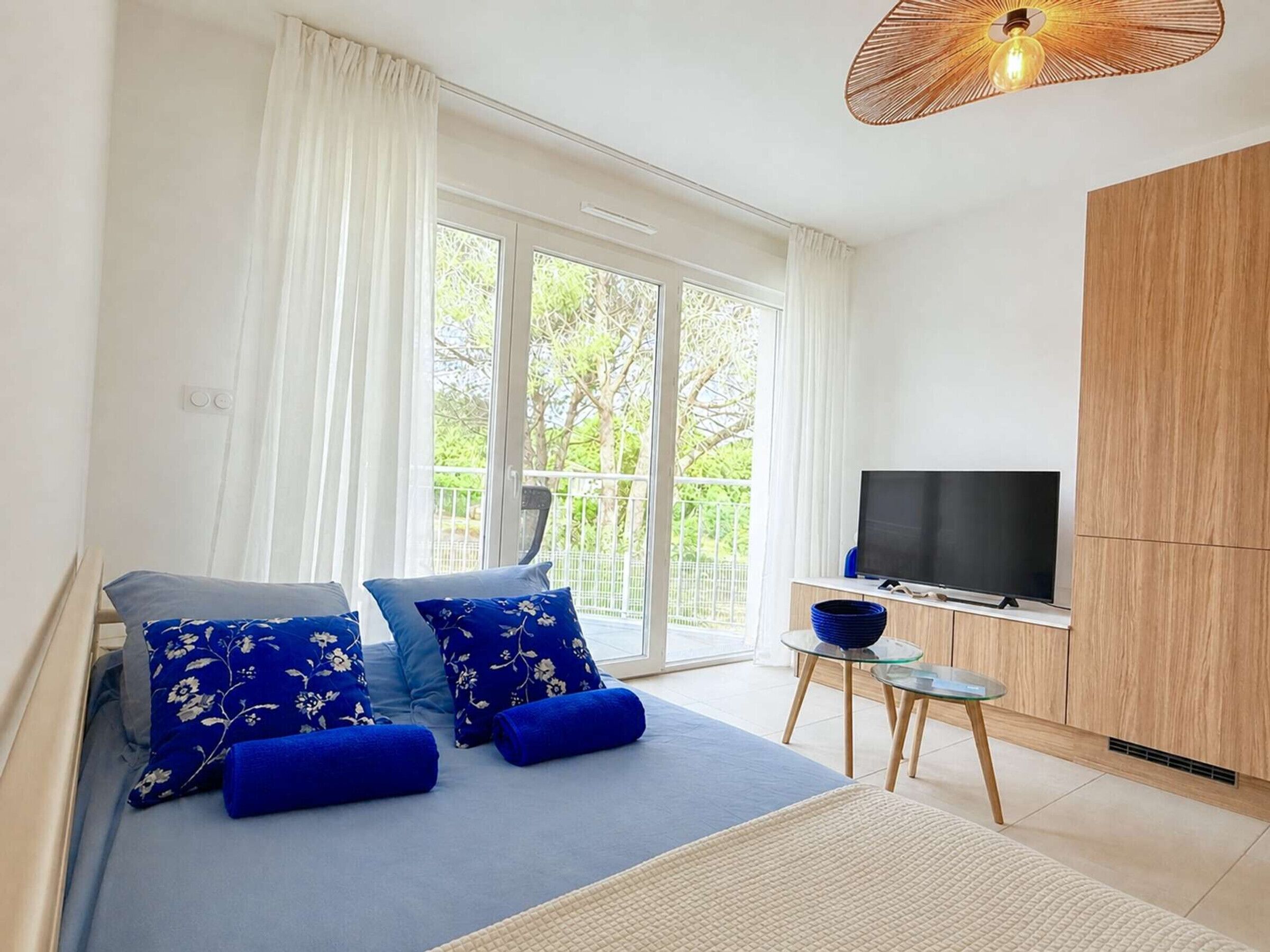 Een slaapkamer met een bed, een televisie en een balkon.