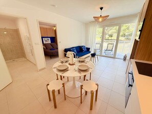 Un coin repas avec une table ronde et des chaises, un canapé et un balcon avec vue.