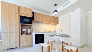 Una cocina moderna con armarios de madera, microondas integrado y comedor con mesa y sillas redondas.