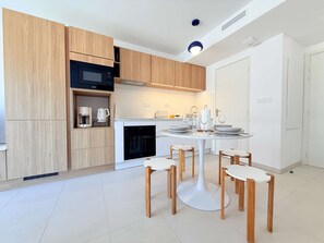 Eine moderne Küche mit Holzausstattung, einer eingebauten Mikrowelle und einem Essbereich mit rundem Tisch und Stühlen.