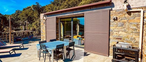Eine Terrassengruppe im Freien mit Tisch, Stühlen, einem Grill und einer Steinmauer.
