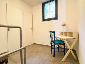 Ein Zimmer mit Schreibtisch, Stuhl und Fenster.