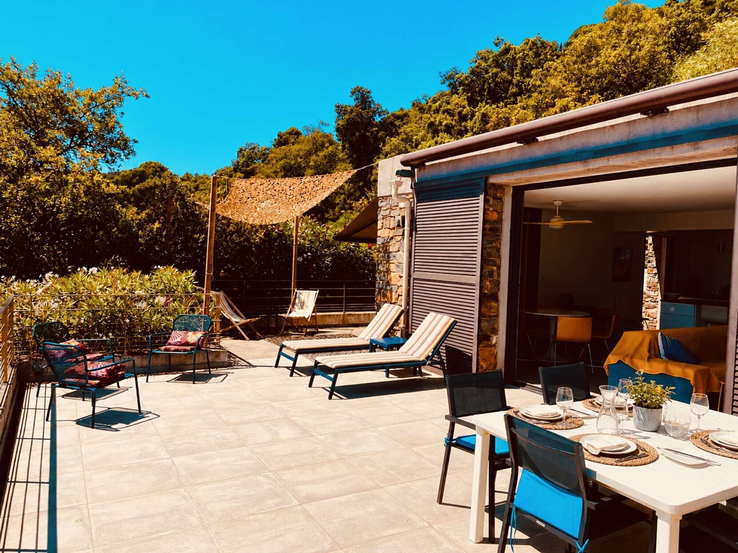 Eine Terrasse im Freien mit Lounge-Möbeln, einem Essplatz für zwei Personen und einer Steinmauer.