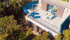 Une maison moderne dotée d’un balcon, d’un coin repas et d’une piscine.