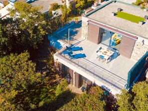 Ein modernes Haus mit Balkon, Essbereich und Pool.