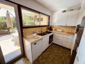 A compact kitchen with a window, white cabinets, a sink, and a dishwasher. - Ground floor apartment, AC - 3 guests (Bormes-les-Mimosas)
