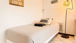 Ein schlicht eingerichtetes Schlafzimmer mit einem Einzelbett, einer Wand-Klimaanlage, einer Stehlampe und einem motivierenden Poster.