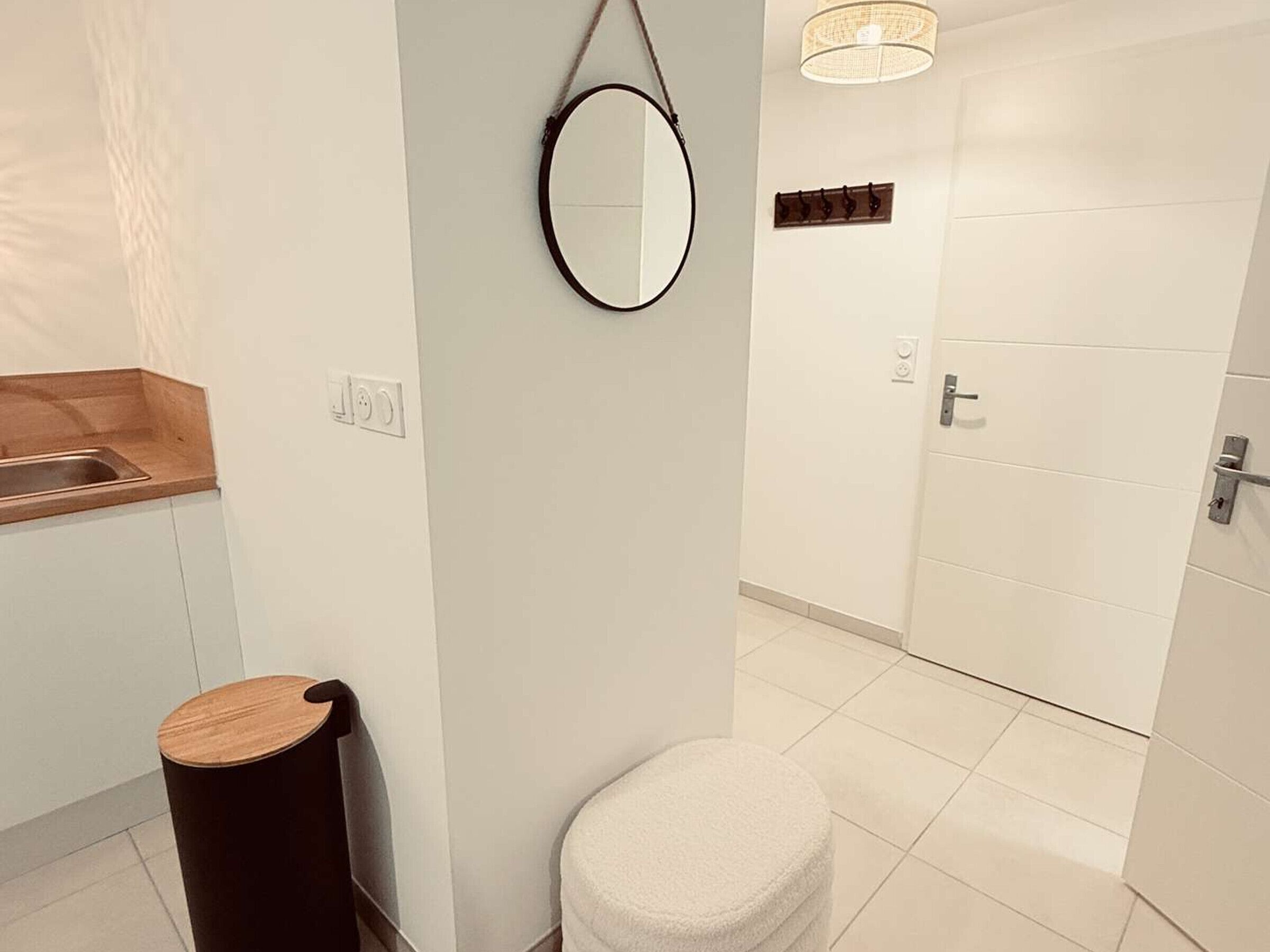 A bathroom with a wooden vanity, a round mirror, a toilet, and a shower area.