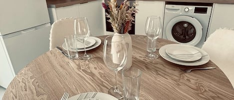 Un comedor con una mesa redonda de madera dispuesta para dos personas, con platos, vasos y cubiertos.