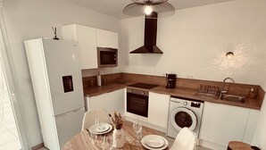 Eine moderne Küche mit Essbereich, ausgestattet mit Kühlschrank, Mikrowelle, Backofen und Waschmaschine.